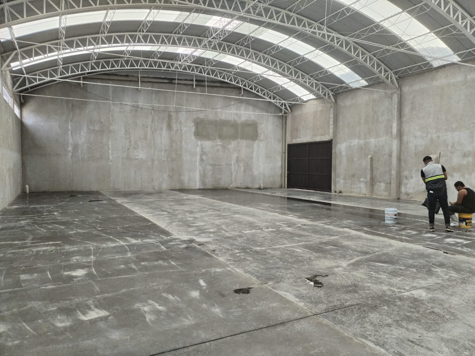 Interior de una construcción con estructura metálica y cubierta amplia